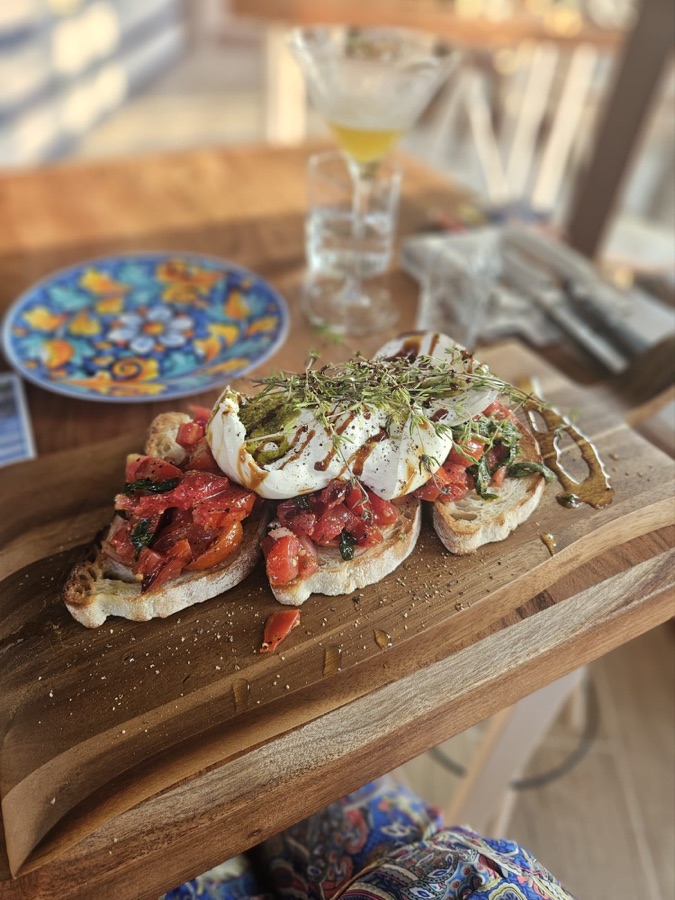 Bruschetta mit Tomaten, Burrata und Kräutern auf dem Holzbrett